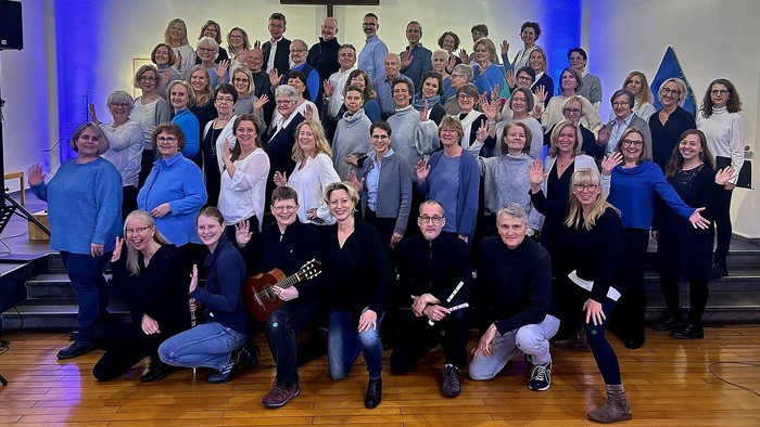 Eine große Gruppe, die fröhlich in einer Kirche posiert, wahrscheinlich nach einem Chor- oder Gemeindeevent.
