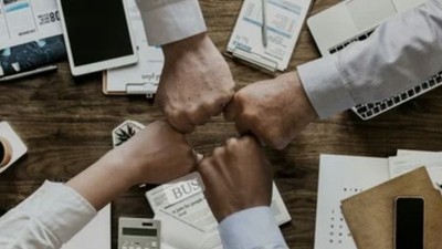 En gruppe af professionelle håndskælder på et kontor med diverse elektronik og papirer.