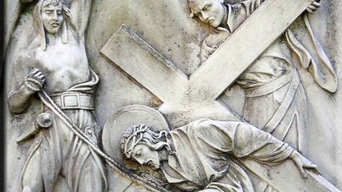 Reliefskulptur, die Jesus beim Tragen des Kreuzes mit begleitenden Figuren auf seinem Kreuzweg darstellt.