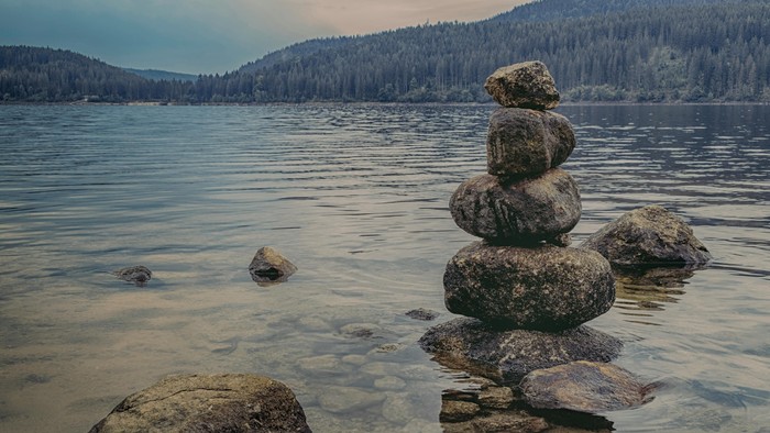 En stelebåde på en klart sjø med skovklædte bjerge i baggrunden