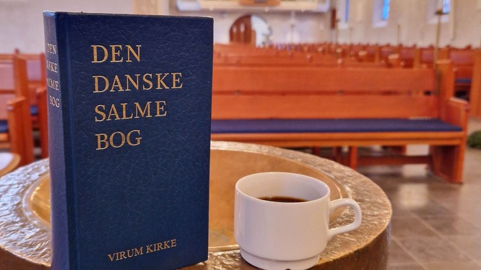 En bog og en tæppe på en terrasse med solnedgang i baggrunden