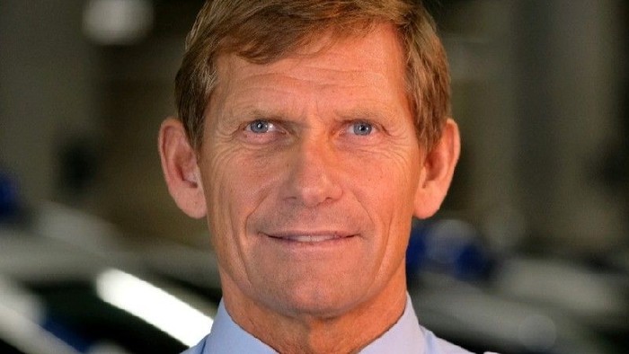 En professionel mand i søfarts- eller marineuniform, der smiler til kameraet.