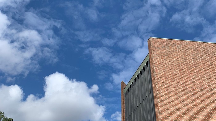 Rød murstensbygning med blå himmel og hvidt skyer