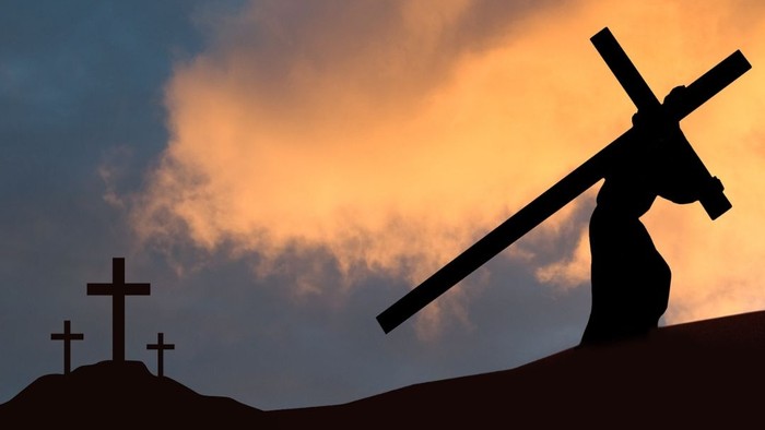 Silhouette von Christus, der das Kreuz trägt, in der Abenddämmerung mit zwei Kreuzen im Hintergrund.
