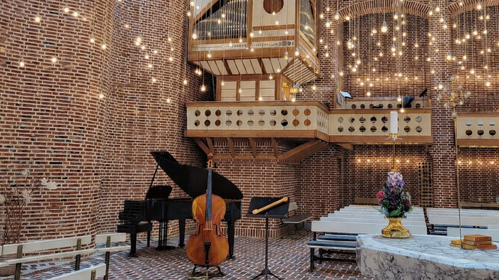 Elegant koncertsal med strygeinstrumenter, indviklet træarkitektur og festlige lyskæder hængende over hovedet.