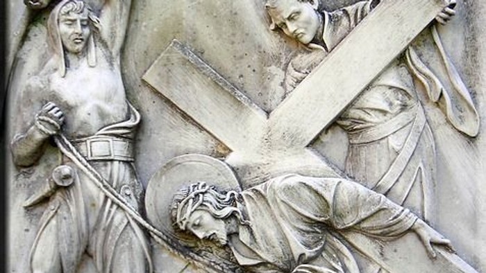 Reliefskulptur, die Jesus beim Tragen des Kreuzes mit begleitenden Figuren auf seinem Kreuzweg darstellt.