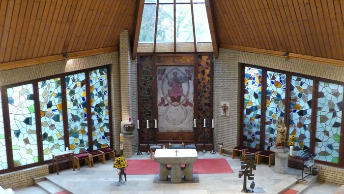 Kircheninneres mit Buntglasfenstern, Altar und Kirchenbänken