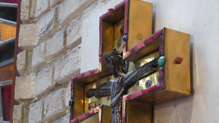 Ein goldgerahmtes Kruzifix an einer weißen Ziegelmauer