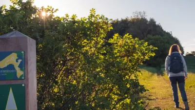 En kvinde går på en sti gennem en naturpark ved solnedgang