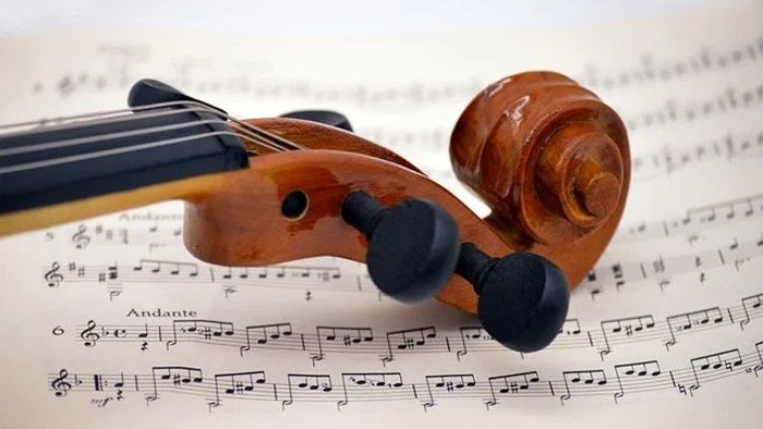 Ein Cello liegt auf Notenblättern, auf denen das Wort *„Andante“* zu sehen ist.