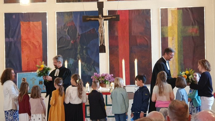 Gottesdienst mit Kindern und Erwachsenen, die sich um den Altar versammelt haben.