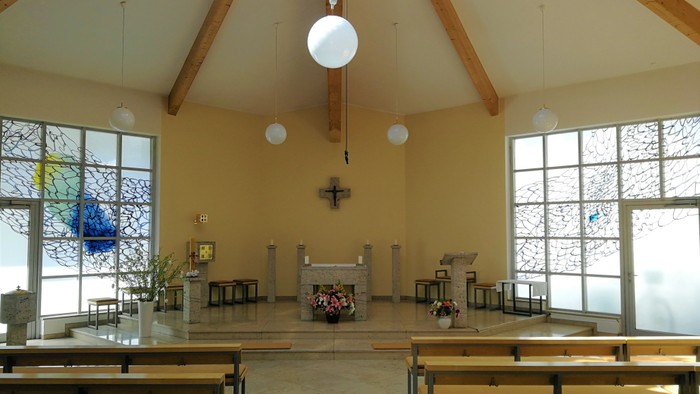 Leere Kirche mit Holzbänken und großen Fenstern