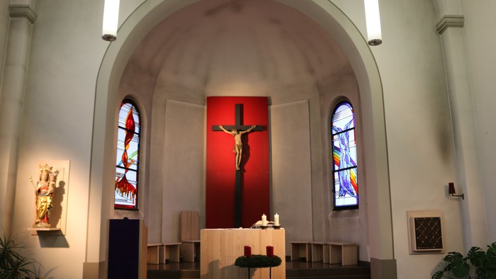 Innenraum einer Kirche mit Kreuzigungsdarstellung und Buntglasfenstern
