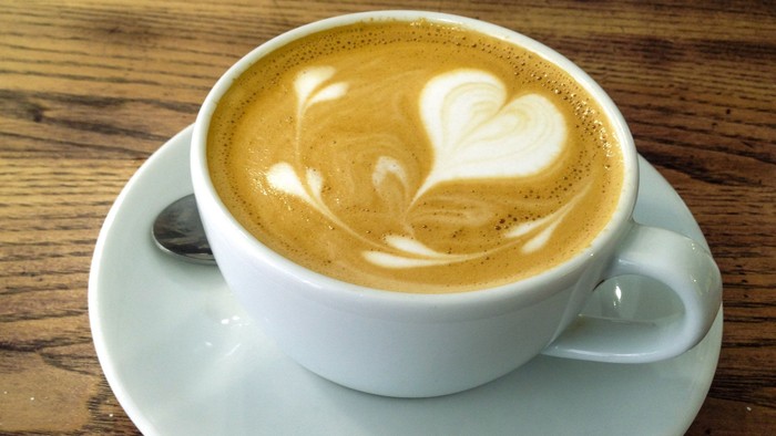 En lille kaffe i en hvid tæppe med mælkesæde i form af et hjerte på.