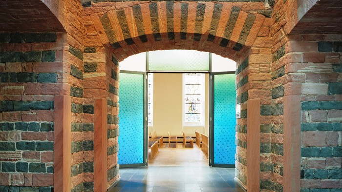 Der Flur hat hohe gewölbte Ziegeldecken und eine blaue Tür am Ende.