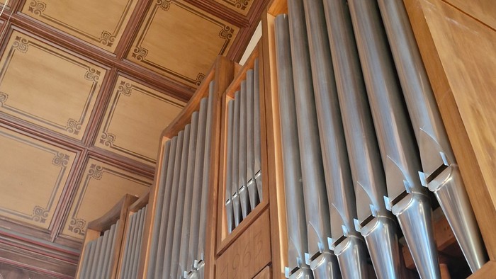 Elegante Pfeifenorgel mit Holzgehäuse und mehreren Reihen metallener Pfeifen in einem prächtigen Innenraum.