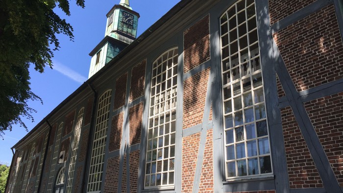 Historisches Backsteingebäude mit hohen Bogenfenstern und einem markanten Uhrturm.