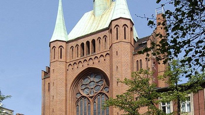 Gothische Backsteinkirche mit zwei Türmen und spitzen Dächern.