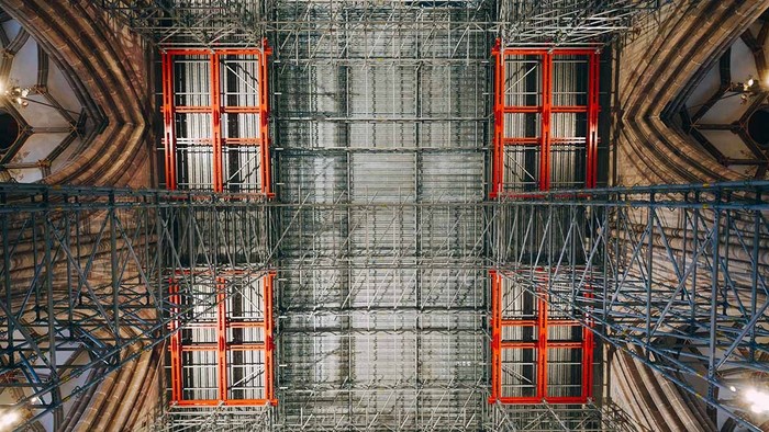 Blick nach oben zum Baugerüst im Ulmer Münster. Das stählerne Baugerüst trifft auf die gotischen Bögen des Bauwerks.