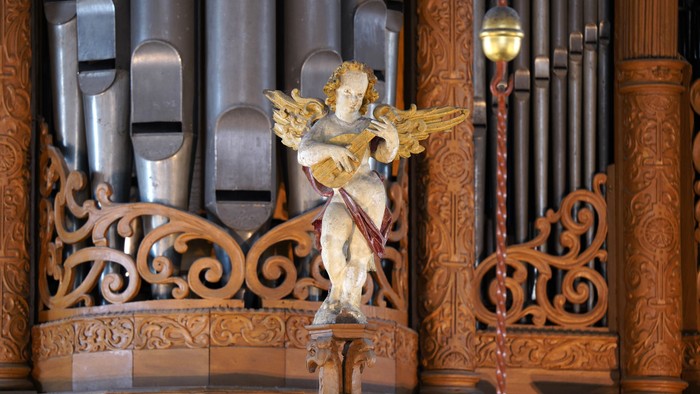 Engelstatue vor einem Holzorgelpfeiler