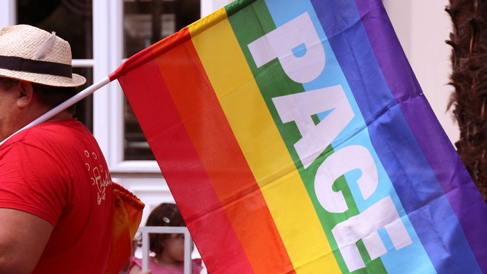 Person hält Regenbogenfahne mit Aufschrift 