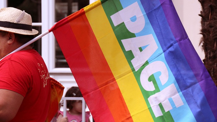 Person hält Regenbogenfahne mit Aufschrift