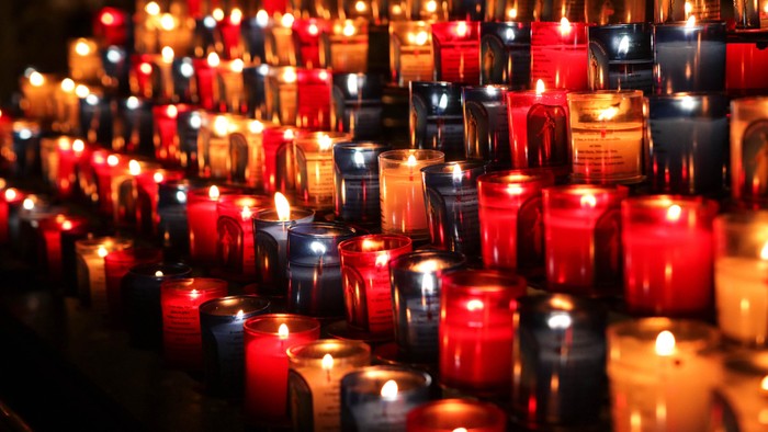 Viele brennende Kerzen in Rot und Weiß, angeordnet in Reihen