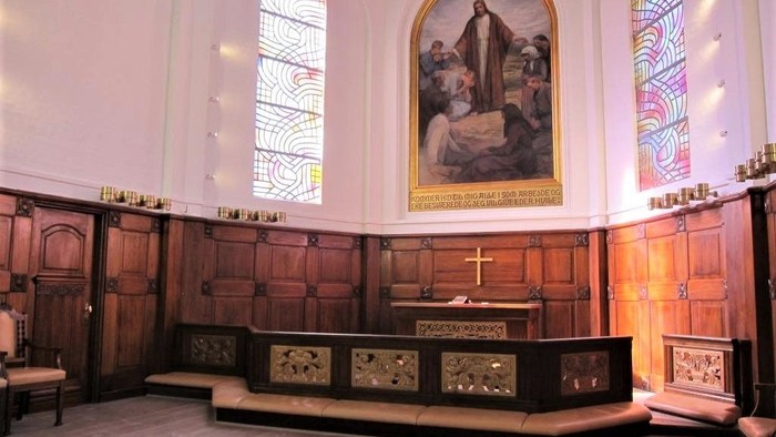 Kirkeinteriør med alter, glasmosaikvinduer og religiøst maleri