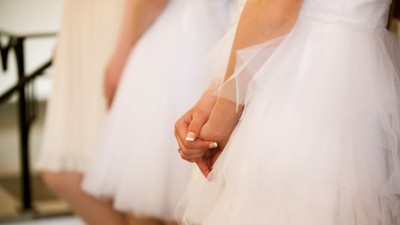 Et nærbillede af en brud, der holder sin brudekjole, mens hun justerer fine stofdetaljer.