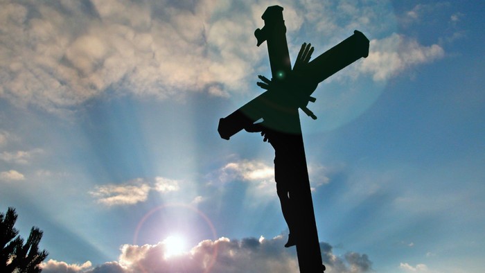 Ein Kreuz vor einem sonnenbeschienenen Himmel