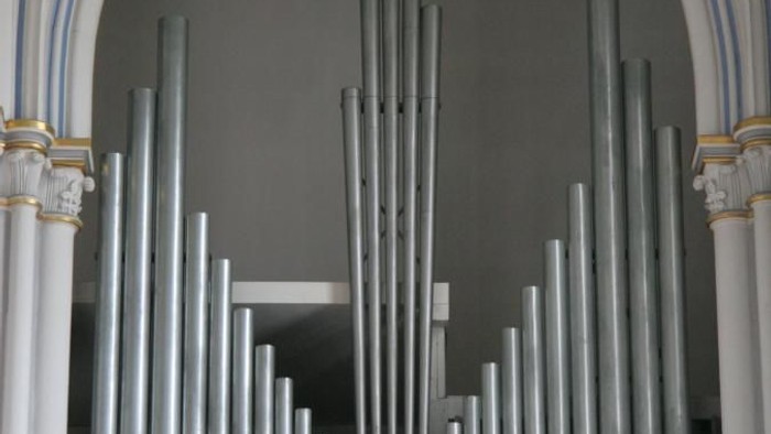 Orgelpfeifen unter einem gewölbten Bogen