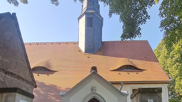 Kleine Kirche mit weißem Zaun und rotem Dach.