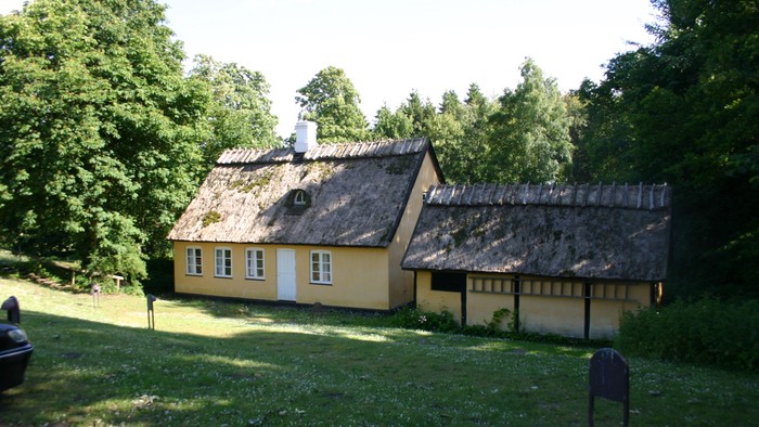 Gul hytte med tagret og skærmbænk foran