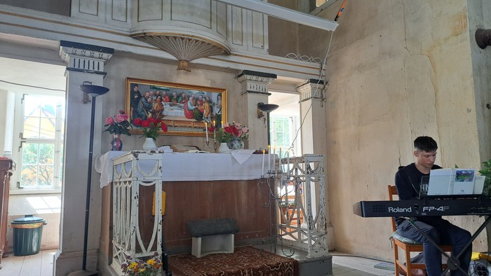 Ein Mann spielt Keyboard in einem Raum mit Altar und Bildern