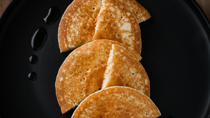 Three crispy tortilla shells on a black plate