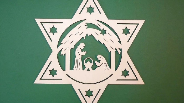 Ein weißes Schneestern-Dekoration mit einer grünen Darstellung der Krippe