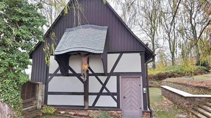 Ein schwarzes und weißes Holzhaus mit lila Tür in einem Garten.