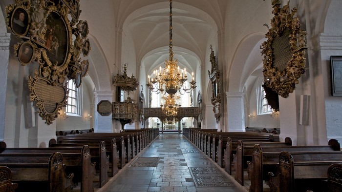 Indre del af kirke med høje vægge og belysning fra kandle.