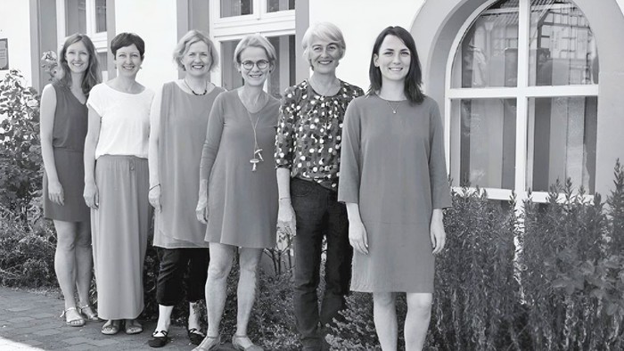 Eine Gruppe von sechs Frauen, die draußen in passender Freizeitkleidung zusammenstehen und für ein Foto posieren.
