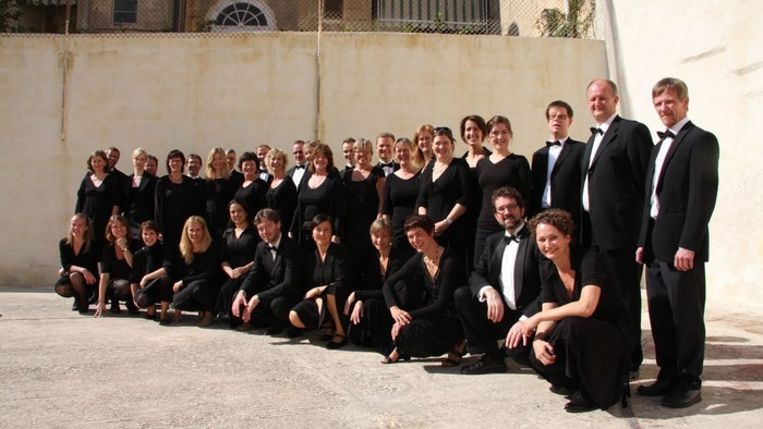 Formel korgruppe poserende sammen i koordineret sort påklædning foran en baggrund af en stenmur.