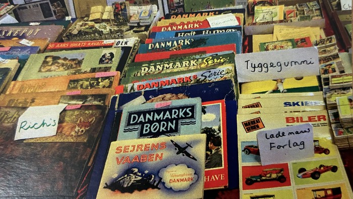 Gamle danske postkort og samlerobjekter arrangeret på et bord med forskellige militære og rejsetemaer.