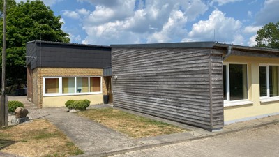 Das Bild zeigt ein modernes Einfamilienhaus mit dunklem Holzfassade und großen Fenstern.
