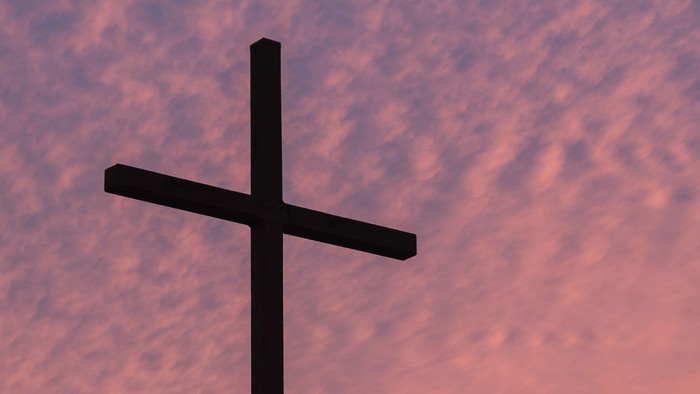 En sort kors med rosa himmel i baggrunden