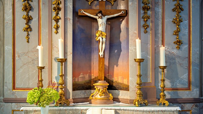 Kirchenaltar mit Kruzifix, Kerzen und Blumen