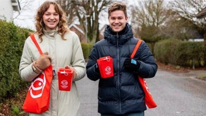 Kvinde og mand ude at gå med indsamlingsbøsser i hænderne, til Folkekirkens nødhjælp 