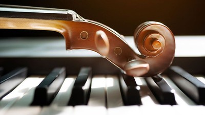 Ein Geigenbogen liegt auf einem Klavier.