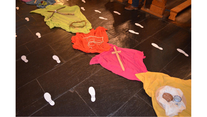 Bunte Kinderkleidung liegt auf einem Boden mit Fußabdrücken.