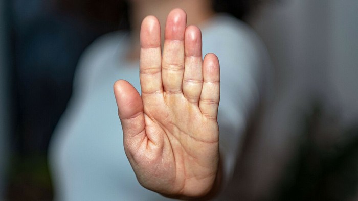 Eine Hand wird ausgestreckt, die Handfläche ist nach außen gerichtet.