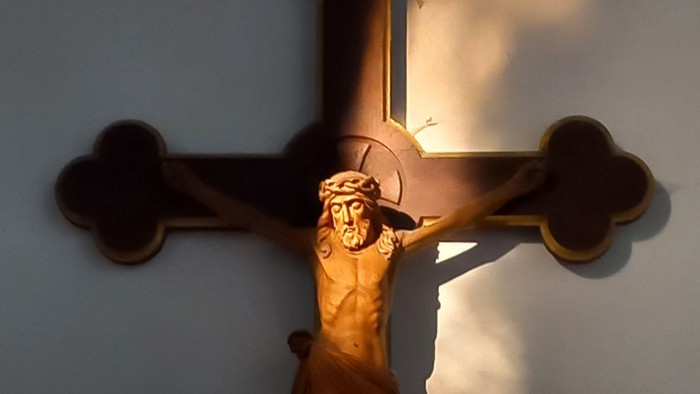 Ein hölzernes Kruzifix an einer blauen Wand.