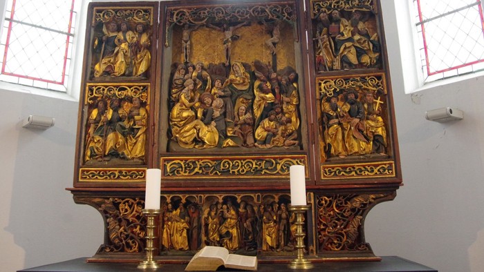 Ein verzierter Altar mit goldenen Darstellungen und Kerzen in einer Kirche